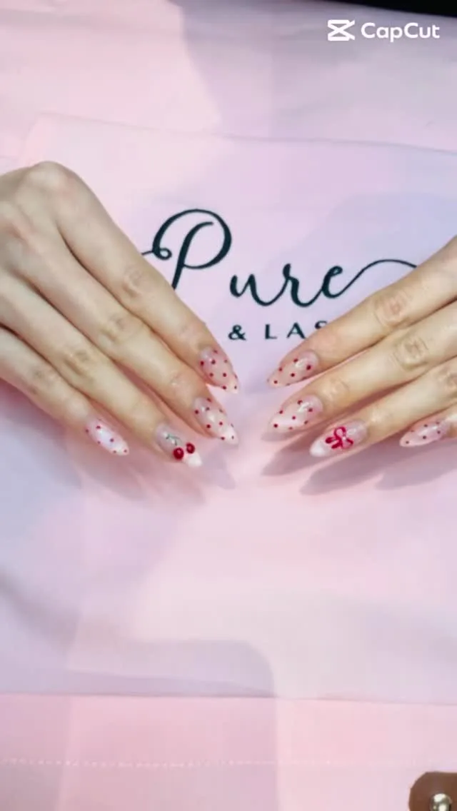 Red-dot and bow nails on the salon's branded Pure & Lashes service cloth
