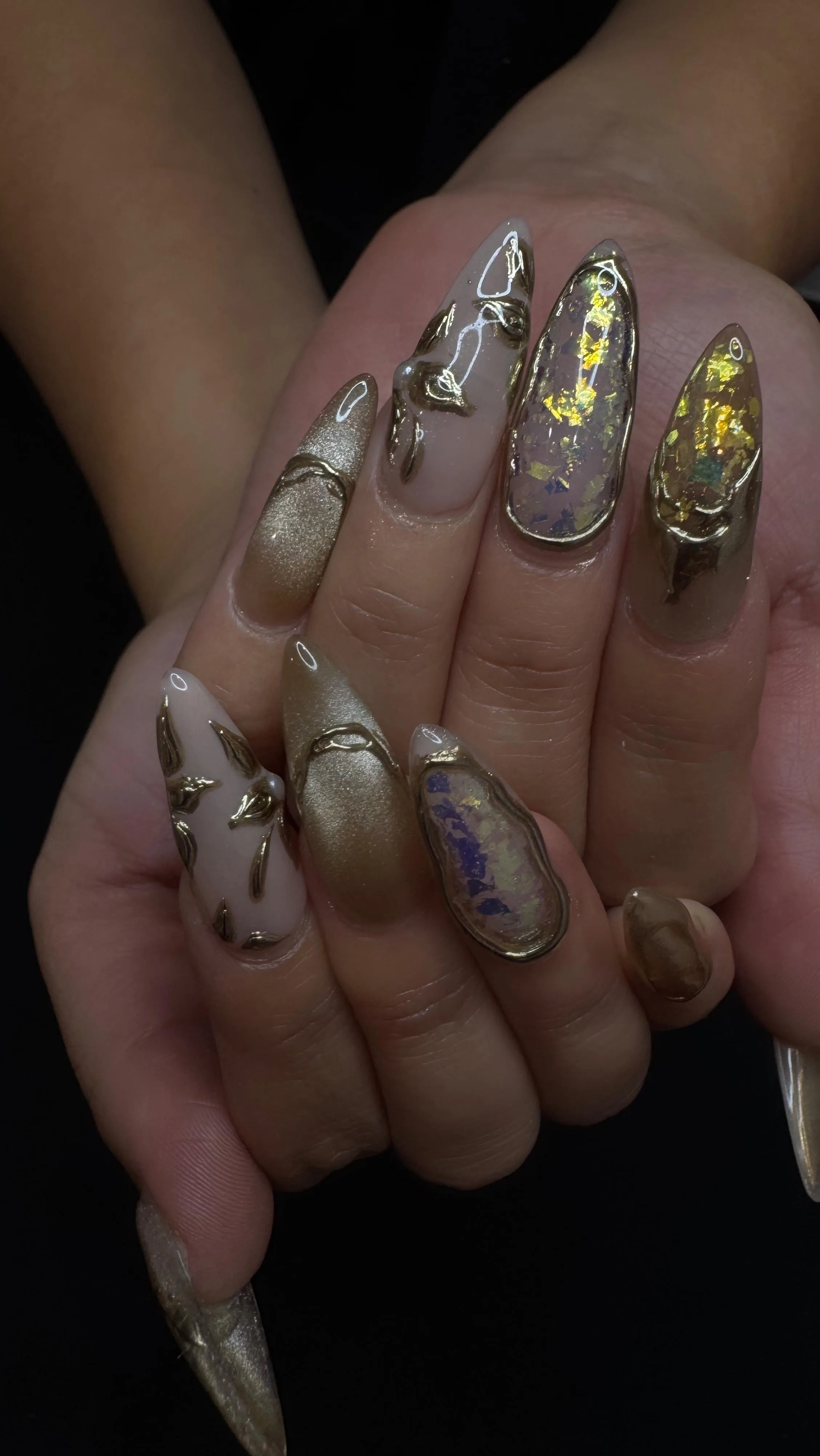 Gold-foil opal stiletto nails with metallic 3D detailing